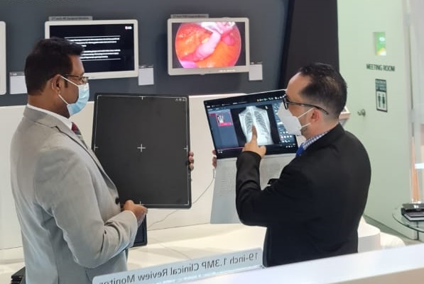 A scenery of demo shop. A person is holding a Digital X-Ray Detector, while another is giving a product guideline