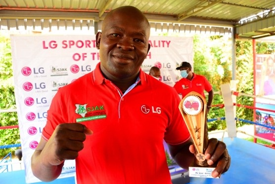 A photo of boxer Elly Ajowi making a proud fighting pose while holding his LG trophy