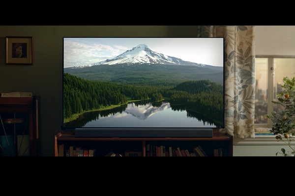 LG's TV displays a beautiful mountain, forest and lake inside a living room.