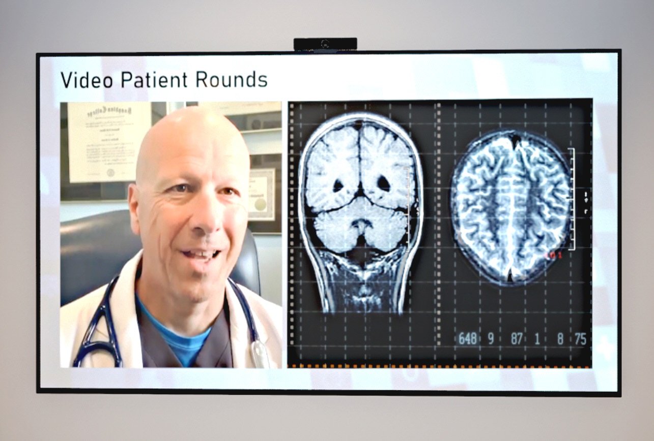 An image of video patient round - A screen displaying a X-ray result and a doctor