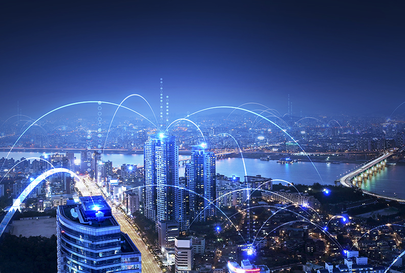 A city skyline at night with buildings connected with blue light to depict telecommunication technology.