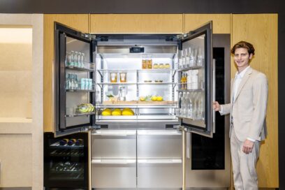 A photo of a man showcasing a french door refrigerator in the SIGNATURE KITCHEN SUITE Kitchen zone at Salone del Mobile