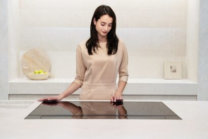 A photo of a woman experiencing a free zone induction hob in the SIGNATURE KITCHEN SUITE Kitchen zone at Salone del Mobile