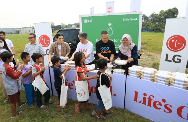 A photo of people handing out  to children waste-free meal kits at a food donation event