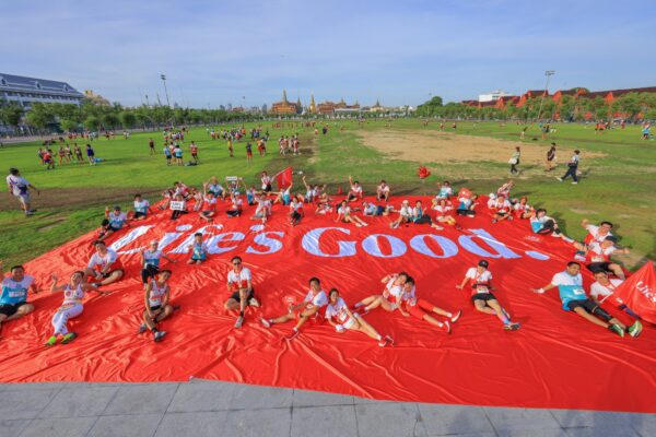 A photo of participants in a 10K Race sit and rest on a large Life's Good banner on the ground