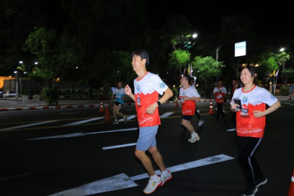 A photo of three people running in a 10K race and laughing in the dark