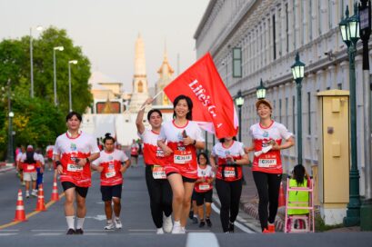 A photo of people running in a 10K Race holding and waving Life's Good banner