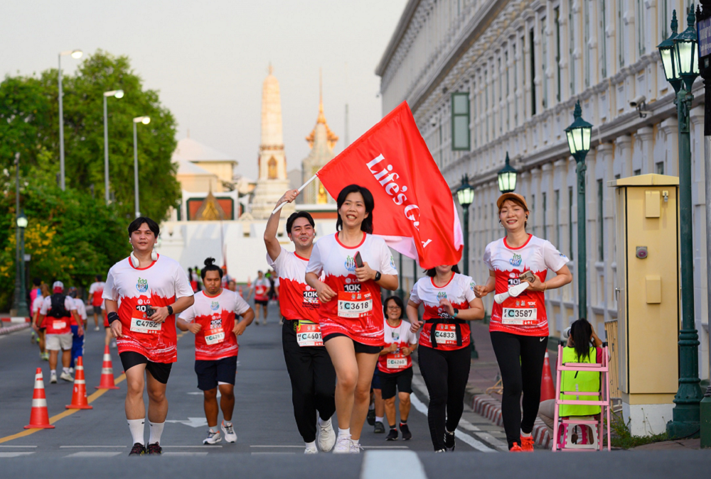 A picture of people running in a 10K Race holding and waving Life's Good banner