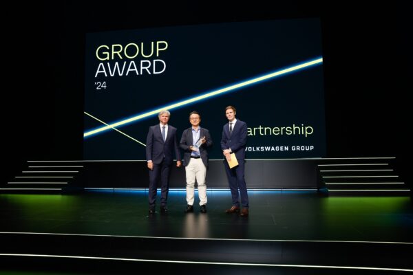 A picture of three men smiling on stage at Volkswagen Group Award 2024