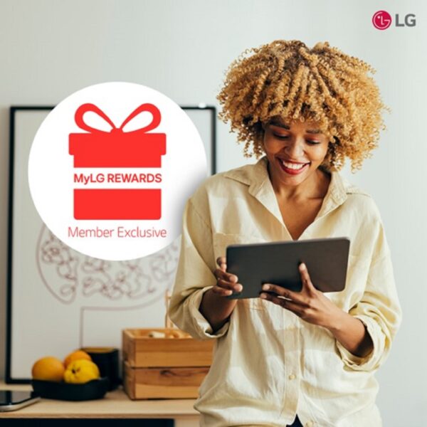 A photo of a woman smiling while looking at MyLg Rewards with a tab 