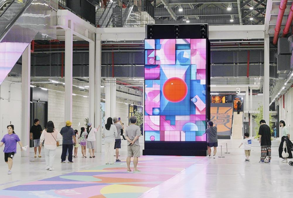 An image of the kinetic LED signage displaying artwork with people walking by