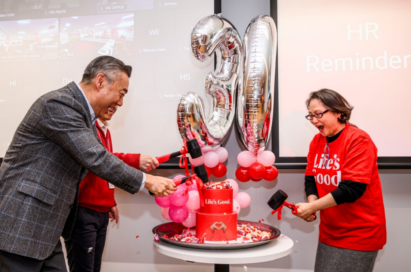 A picture of LG employees cutting the cake together