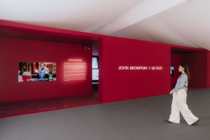 A woman walks toward the exhibition area to read information about the collaboration between John Akomfrah and LG OLED